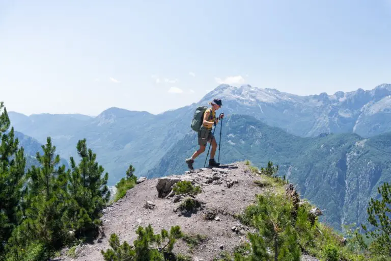 hiker with backpack and poles on mountain ridge