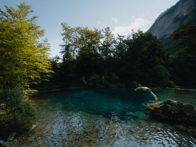 Wandelaar die zwemt in de Blue Eye - Balkan Trail